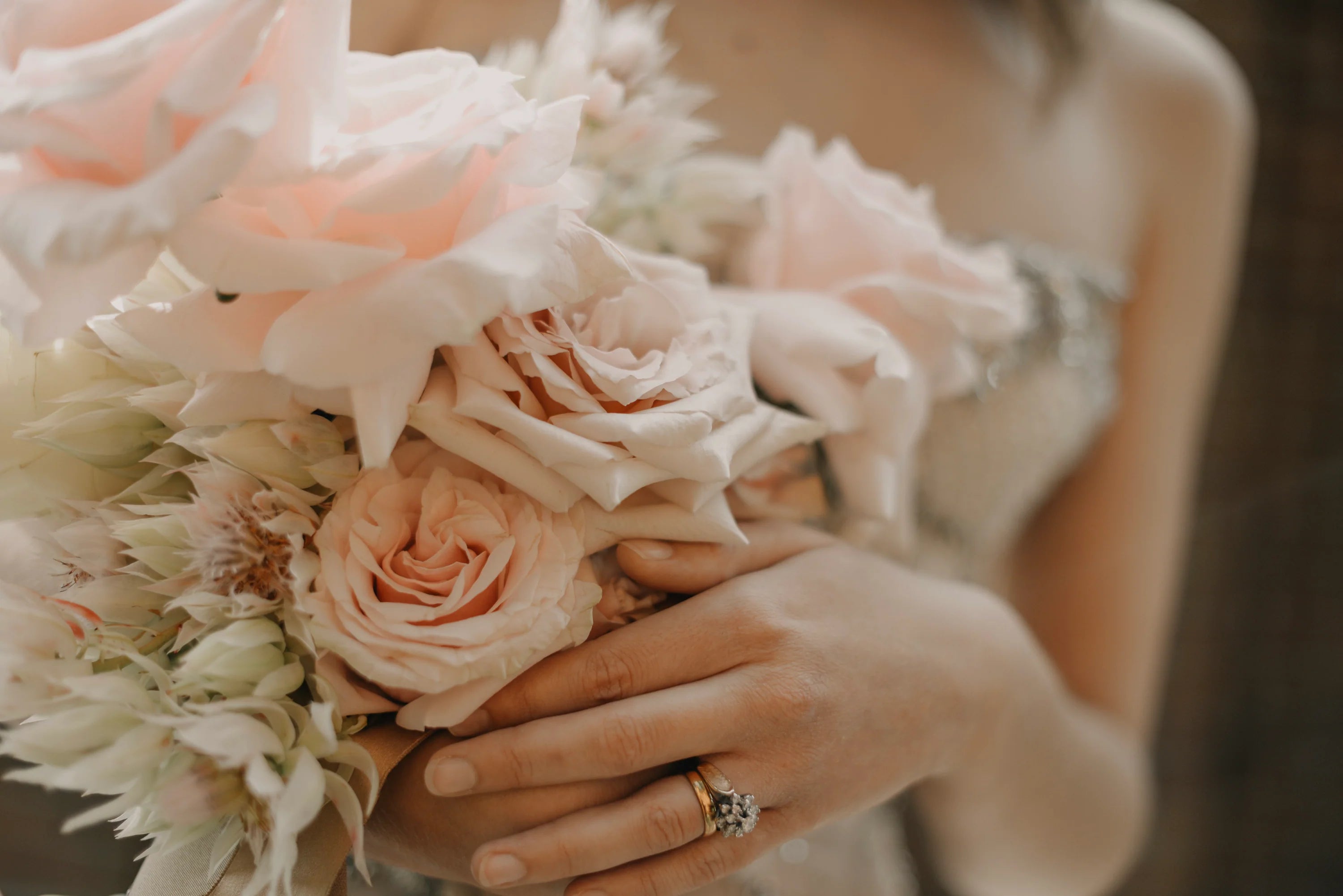 A close-up of a bride holding her wedding bouquet with her ring on display.
