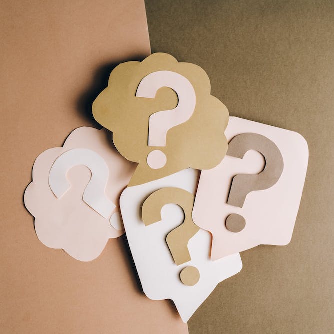 Series of cardboard cutout question marks arranged together.