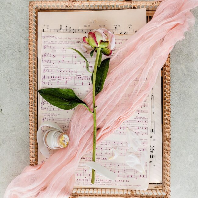 Flat lay of a rose placed on sheet music.